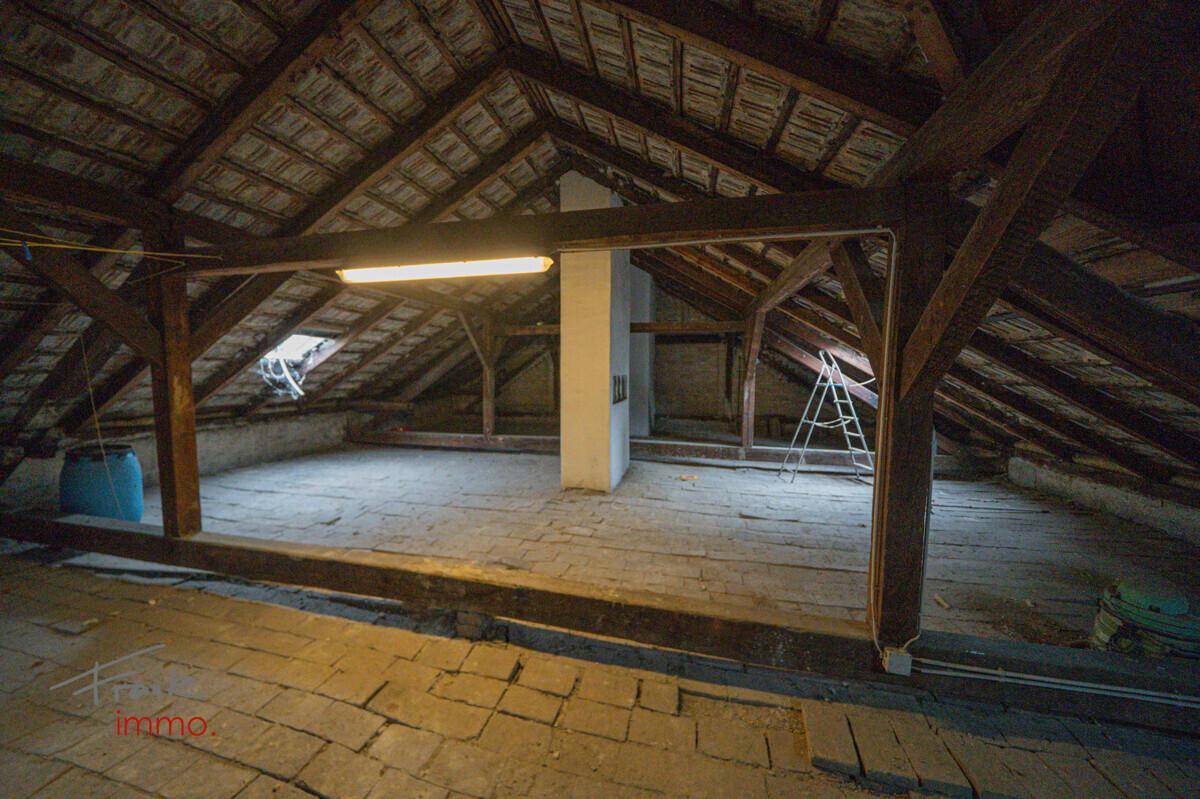 Geräumiger Dachboden mit sichtbaren Holzbalken und Ziegeln, bietet Ausbaupotenzial.
