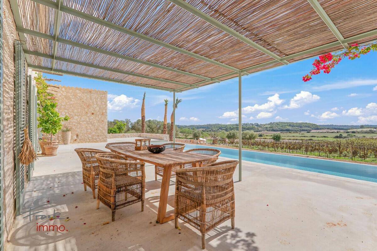Überdachter Essbereich im Freien mit Holztisch und Korbstühlen, direkt am Pool mit Weinbergblick.