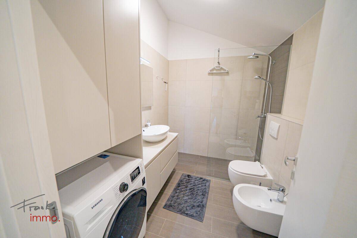 Modernes Badezimmer mit Waschmaschine, begehbarer Dusche und Bidet.