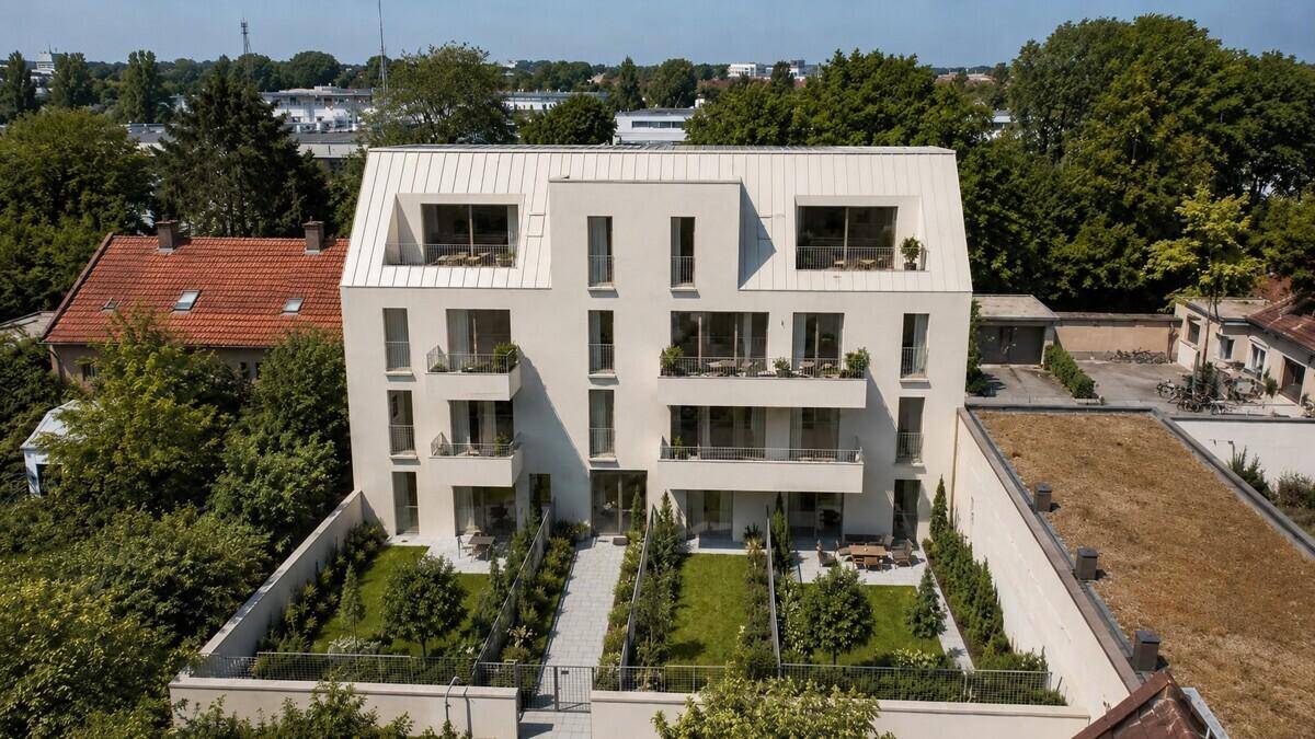 Luftaufnahme des modernen Wohngebäudes mit gepflegten Gärten und umliegender Bebauung.