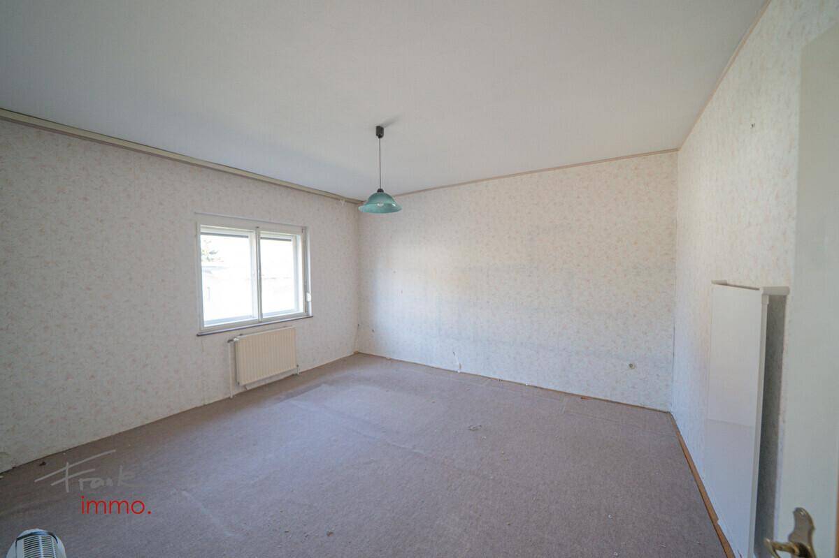 Geräumiges Zimmer mit Teppichboden und weißer Tapete, bereit zur individuellen Gestaltung und Modernisierung.