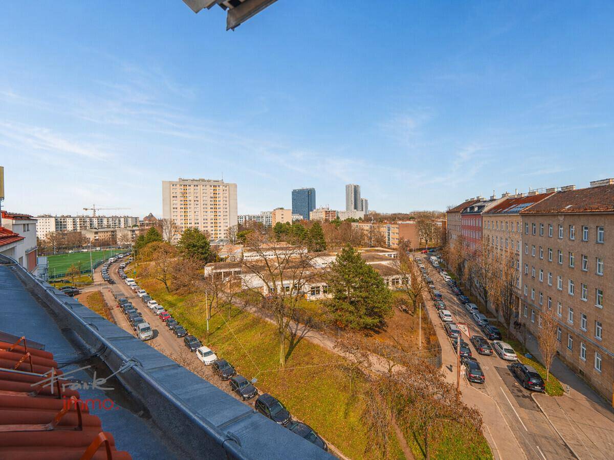 Weitläufiger Blick über die städtische Umgebung mit Gebäuden, Straßen und Grünflächen.