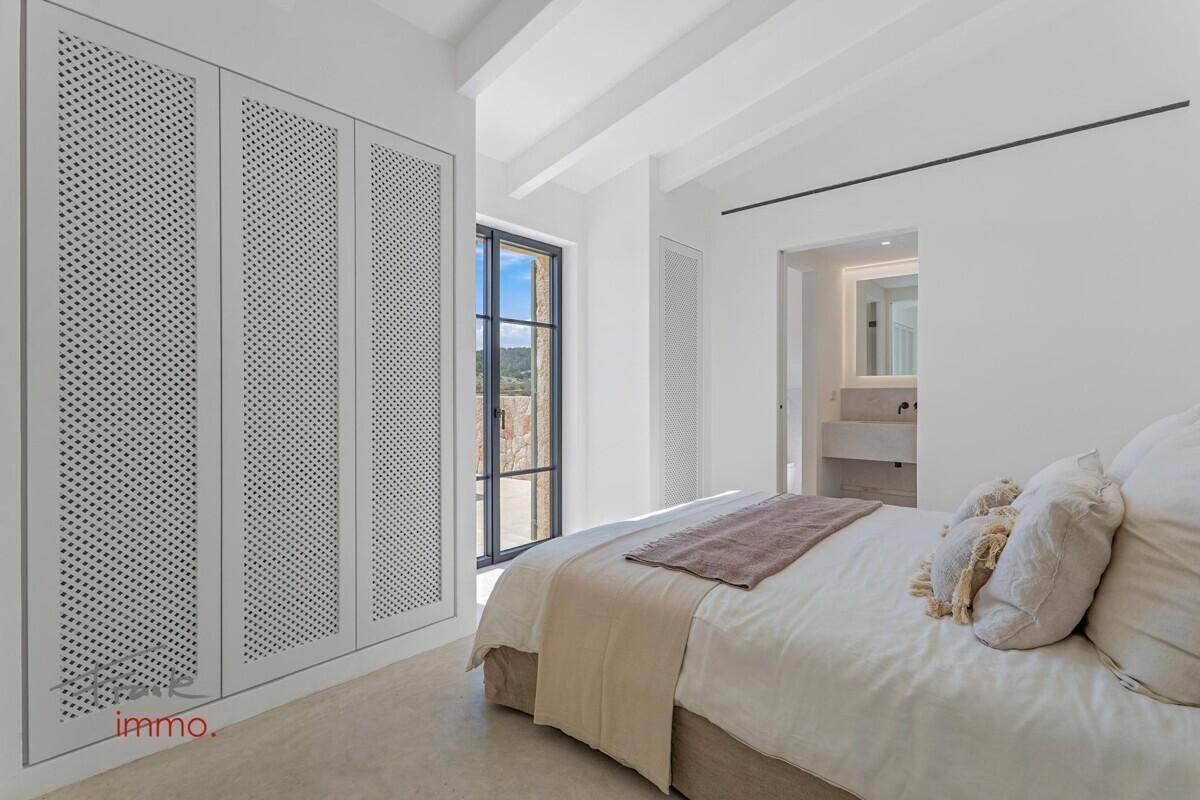 Schlafzimmer mit integriertem Kleiderschrank, großem Fenster und Zugang zu einem Bad en suite.