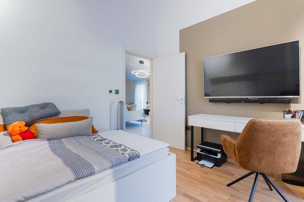 Helles Schlafzimmer mit Einzelbett, Schreibtisch und Blick in den Wohnbereich.