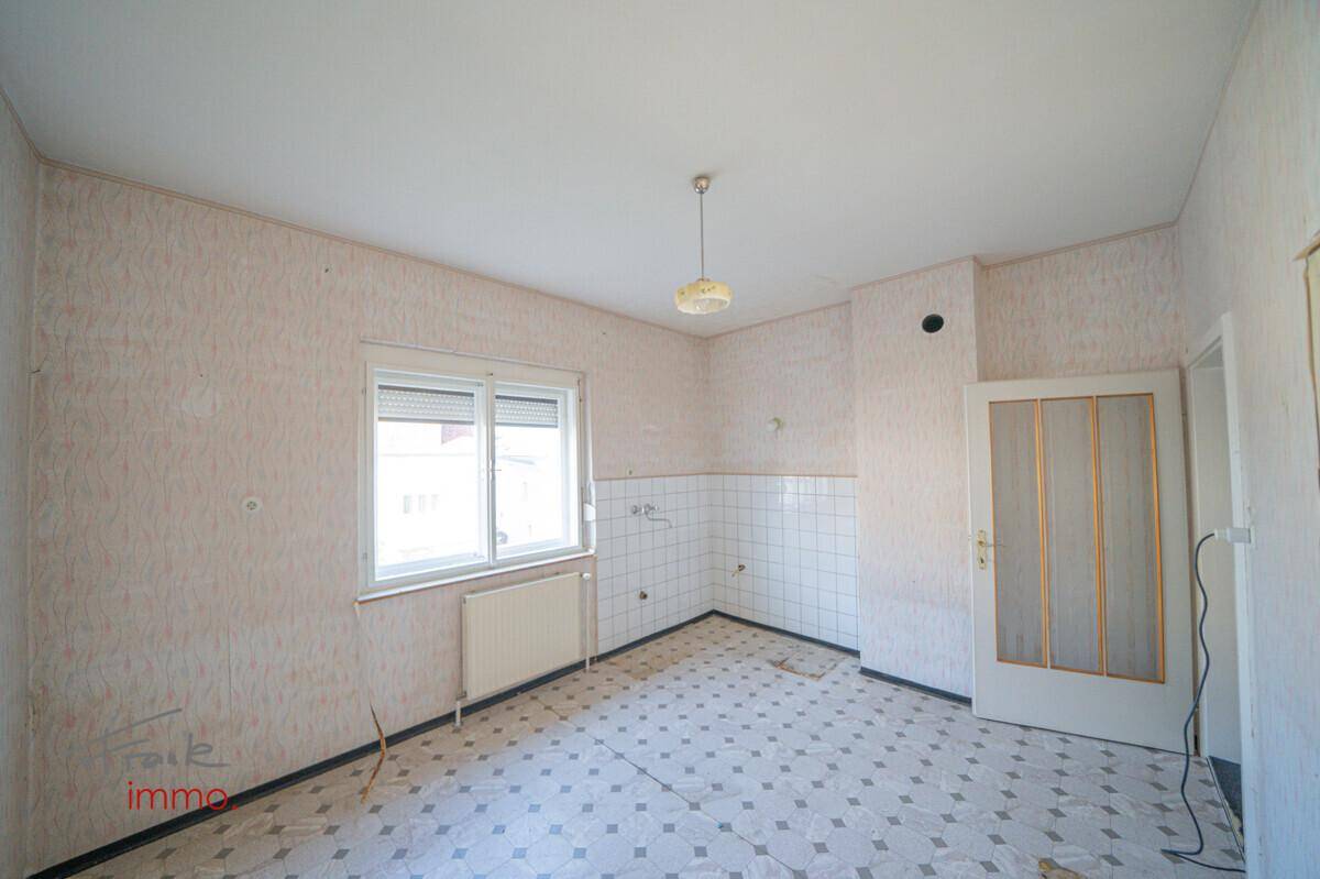 Helle Küche mit Fenster, alten Boden- und Wandfliesen, bietet viel Potenzial für eine neue Einrichtung.