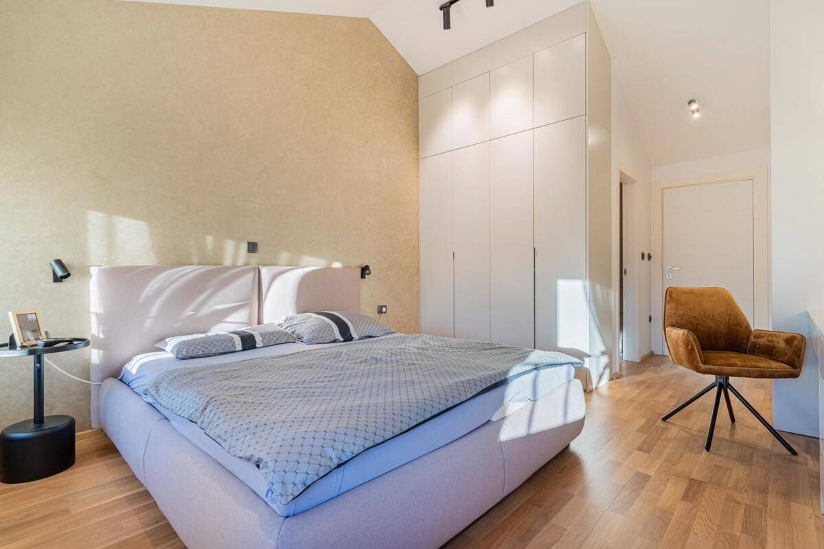 Modernes Schlafzimmer mit Doppelbett, Holzboden und integrierten Kleiderschränken.