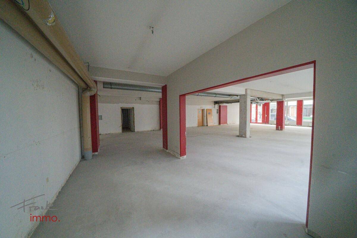 Innenansicht eines weiteren Bereichs des Gewerberaums mit weißen Wänden und Betonboden.