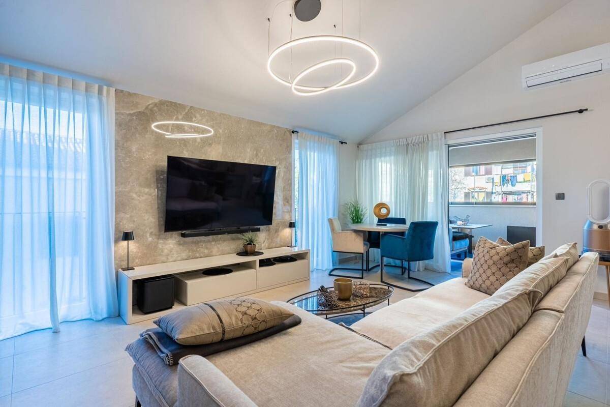 Lichtdurchfluteter Wohn- und Essbereich mit beigem Sofa, Esstisch und Zugang zu einem Außenbereich.