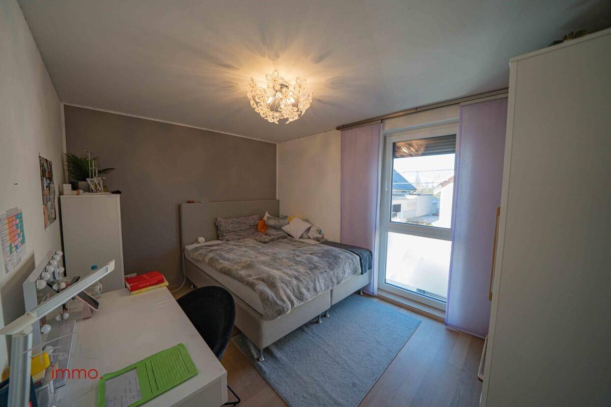 Schlafzimmer mit Doppelbett, Schreibtisch und modernem Kronleuchter.