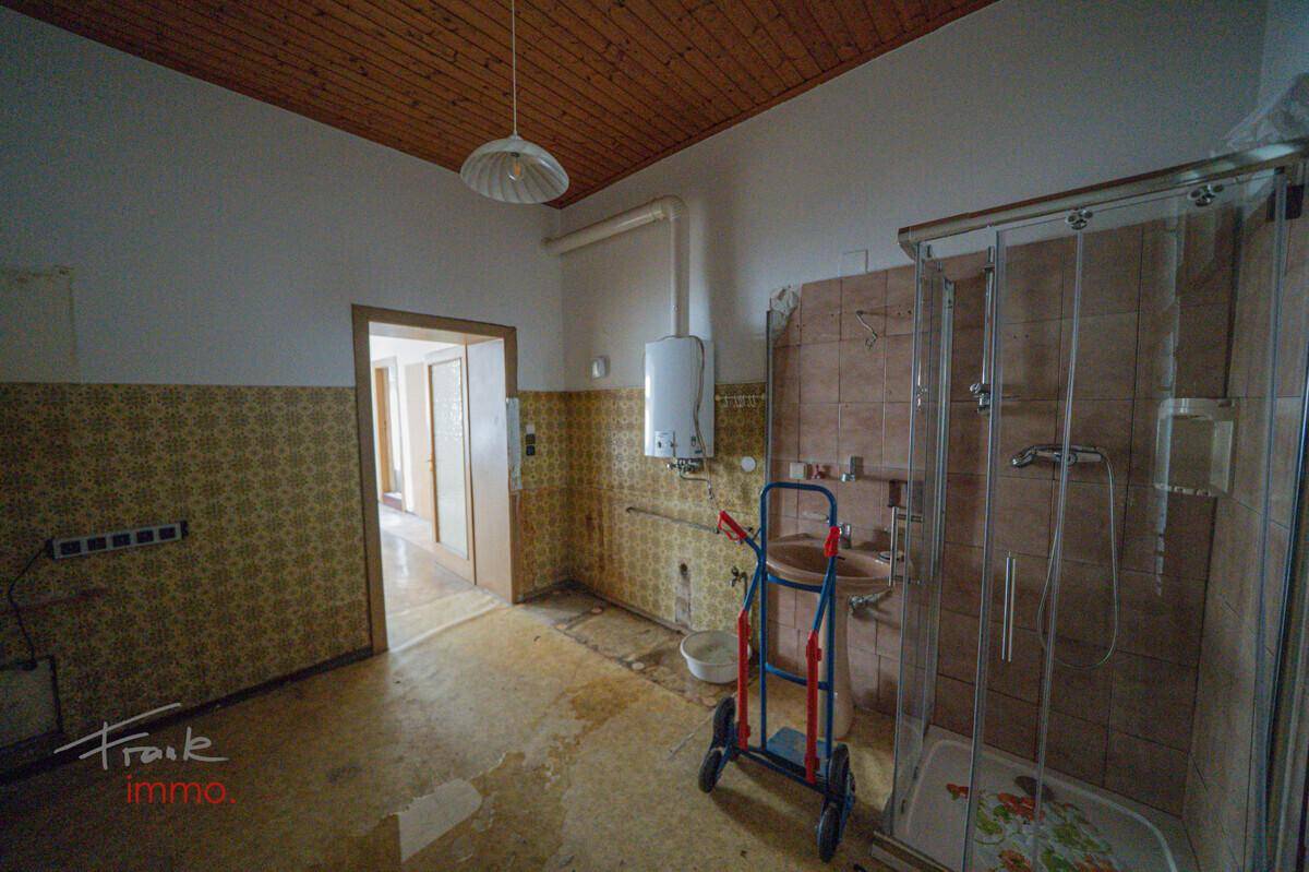 Badezimmer in Renovierungsbedarf mit Duschkabine, Waschbecken und Warmwasserbereiter.