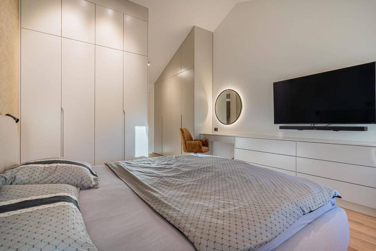 Modernes Schlafzimmer mit Doppelbett, Holzboden und großen Einbauschränken.