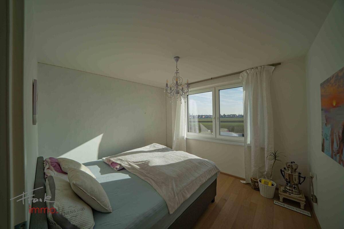 Schlafzimmer mit Doppelbett, Parkettboden und sonnigem Ausblick.
