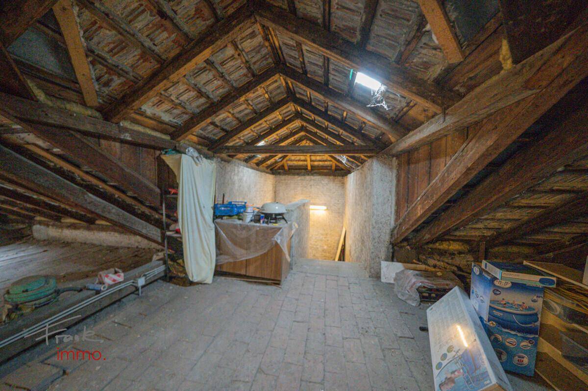 Langer Dachboden mit sichtbarer Holzkonstruktion und Ziegeln, der auf einen Ausbau wartet.