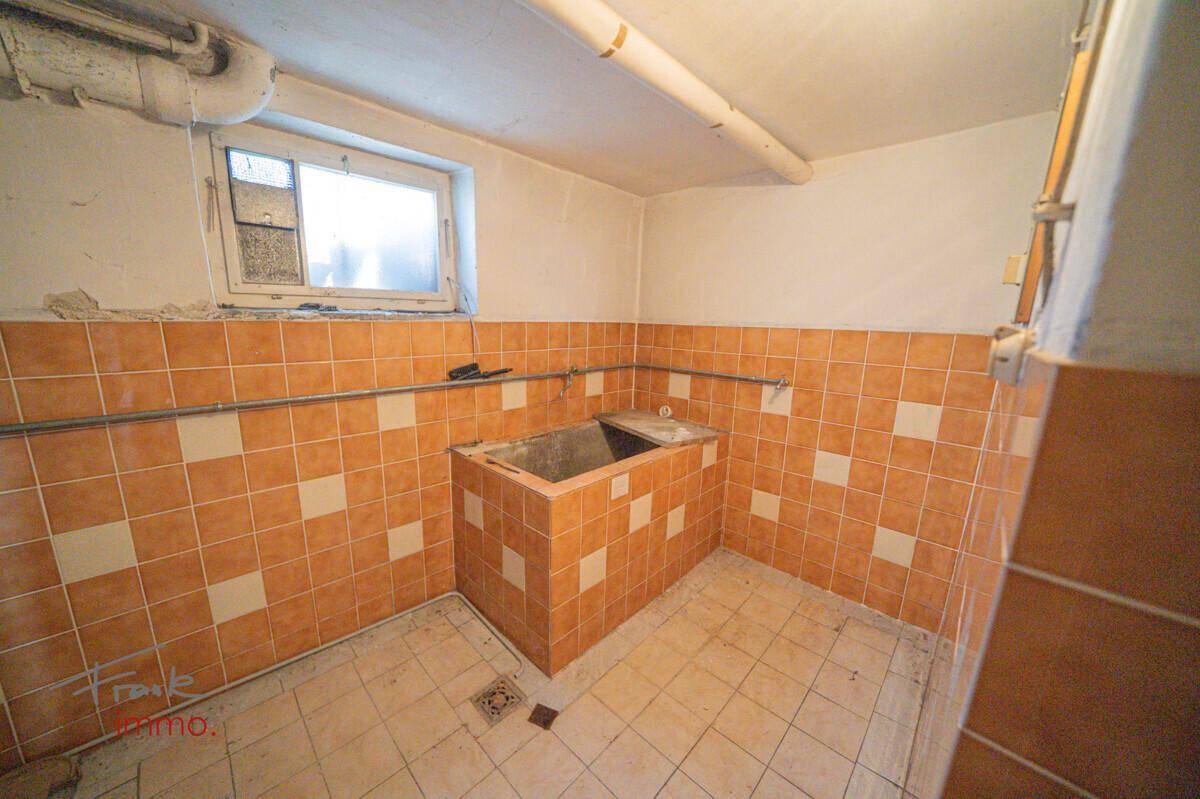 Kellerraum mit großem gemauertem Waschbecken und gefliesten Wänden, ideal für handwerkliche Arbeiten.