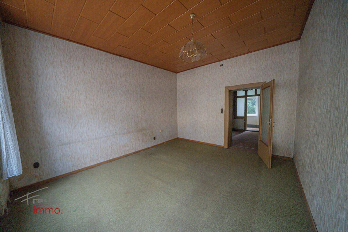 Raum mit Teppichboden, Holzpaneeldecke und einem Fenster mit Vorhängen.