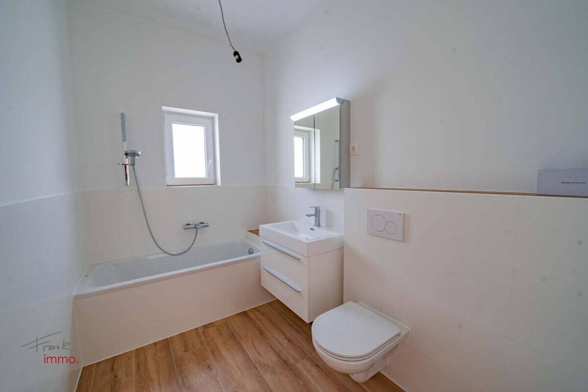 Modernes Badezimmer mit Badewanne, Waschbecken, Toilette und Spiegelschrank.