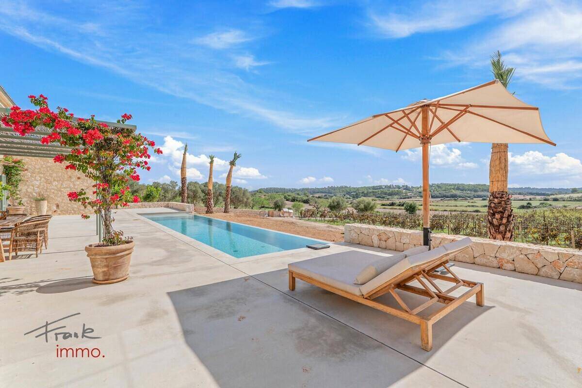Sonnige Terrasse mit Liegestuhl, Sonnenschirm und langem Pool mit weitem Blick über die Landschaft.