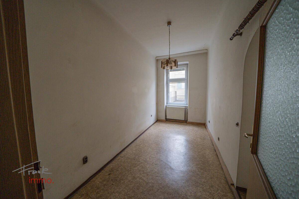 Schmaler Raum mit Linoleumboden und einem Fenster, das natürliches Licht hereinlässt.