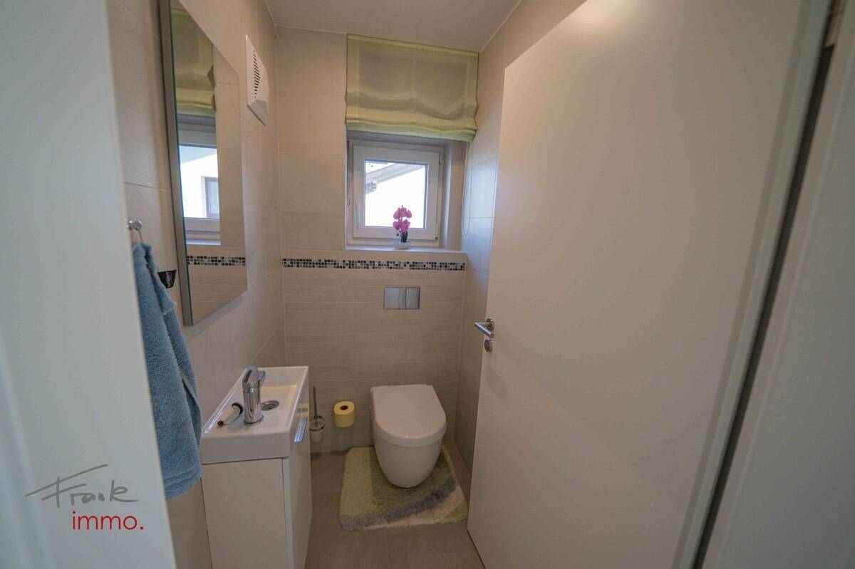 Modernes Gäste-WC mit wandhängendem WC, kleinem Waschbecken und Fenster.
