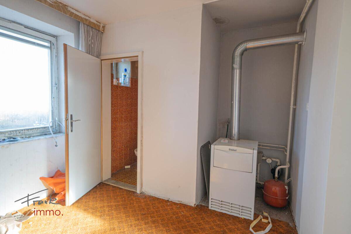 Hauswirtschaftsraum mit Heizungsanlage und Zugang zu einem kleinen Badezimmer.