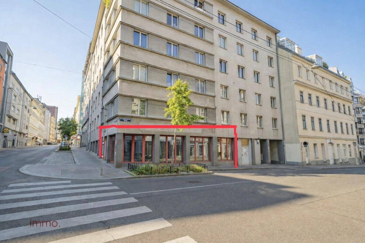 Gesamtansicht des Eckgebäudes mit roten Fensterrahmen und einer Markierung des Gewerbebereichs.