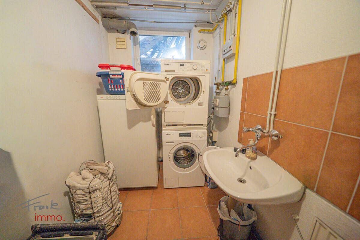 Praktischer Hauswirtschaftsraum im Keller mit Waschmaschine, Trockner und Waschbecken.