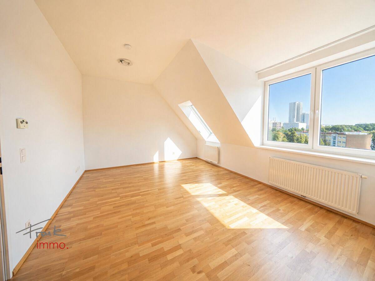 Helles Dachgeschosszimmer mit Parkettboden und weitem Blick über die Stadt, sonnendurchflutet.