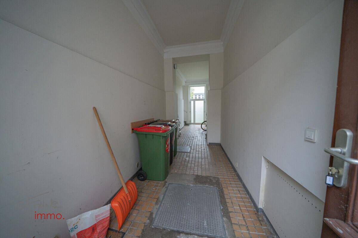 Eingangsbereich mit Fliesenboden und Mülltonnen, führt zu einer weiteren Tür.