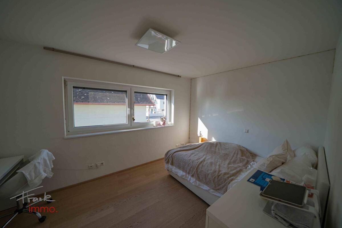 Helles Schlafzimmer mit Parkettboden und Blick auf die Umgebung.