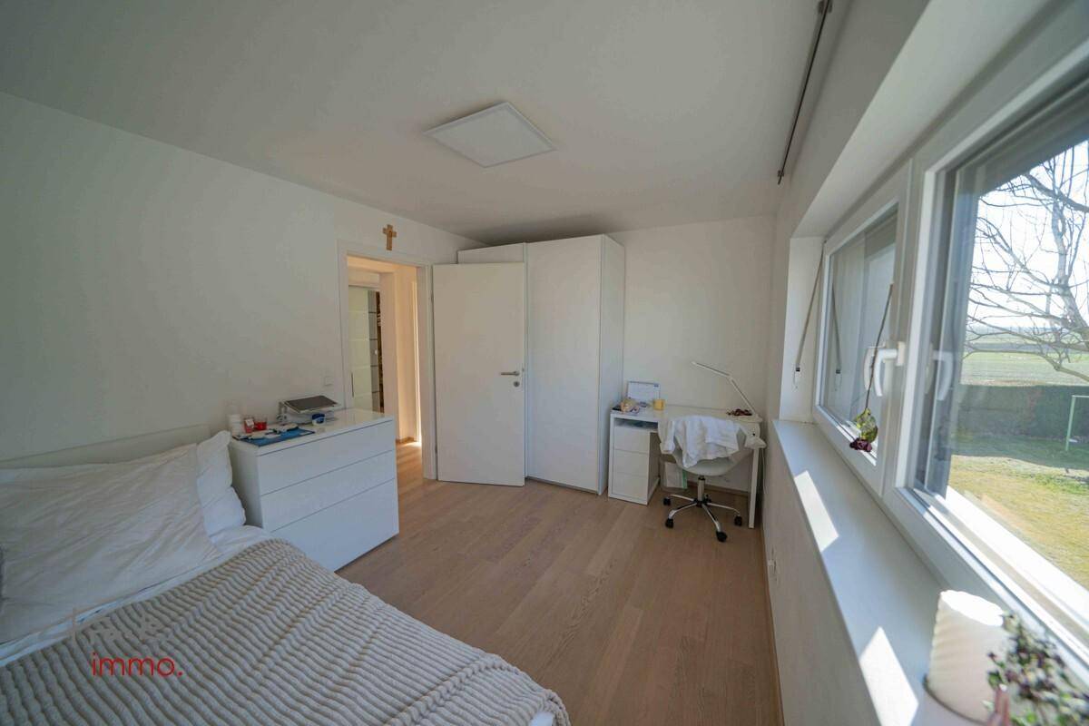 Schlafzimmer mit Einzelbett, Schreibtisch und großem Fenster.