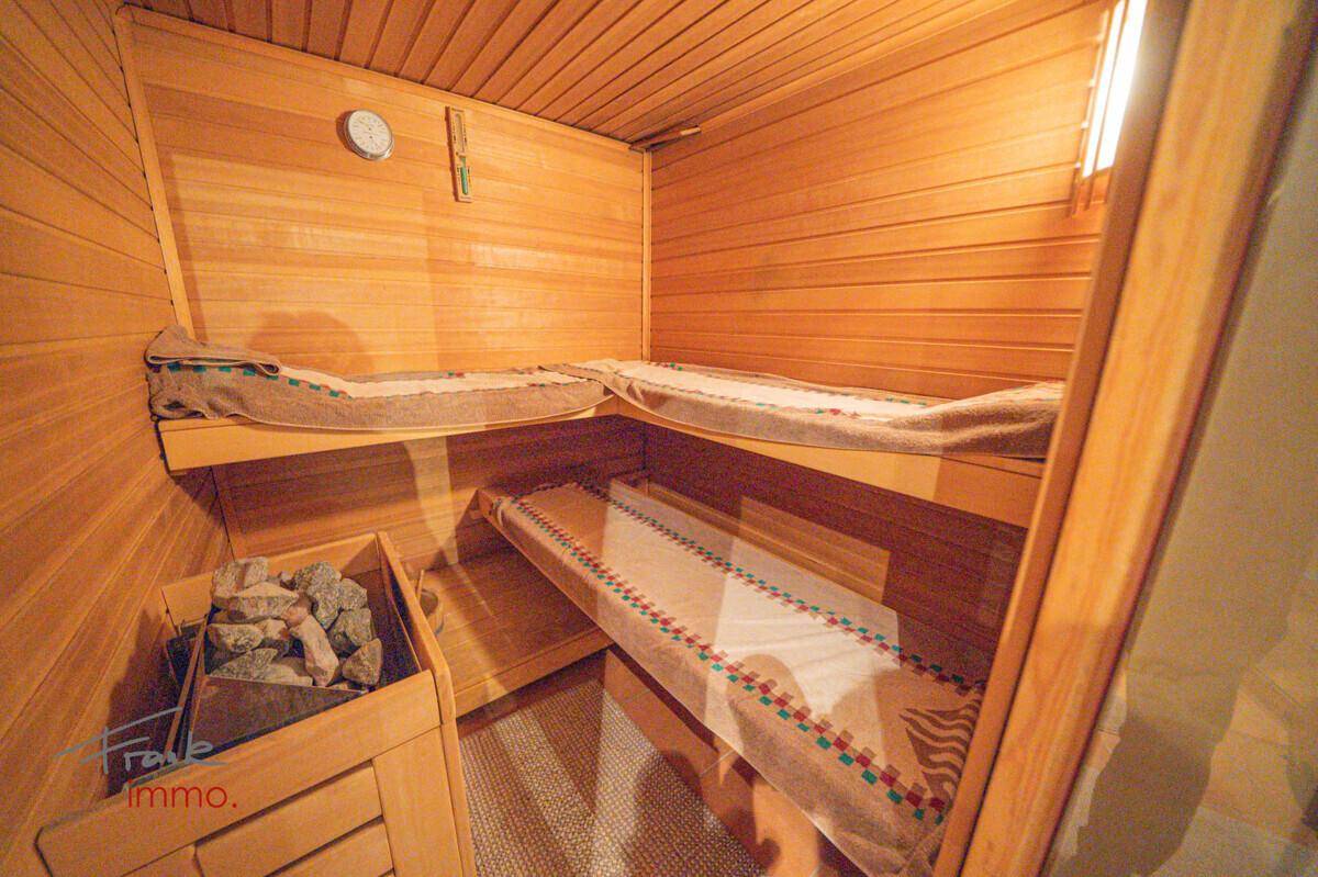 Gemütliche Holzsauna mit mehreren Bänken und traditionellem Saunaofen.