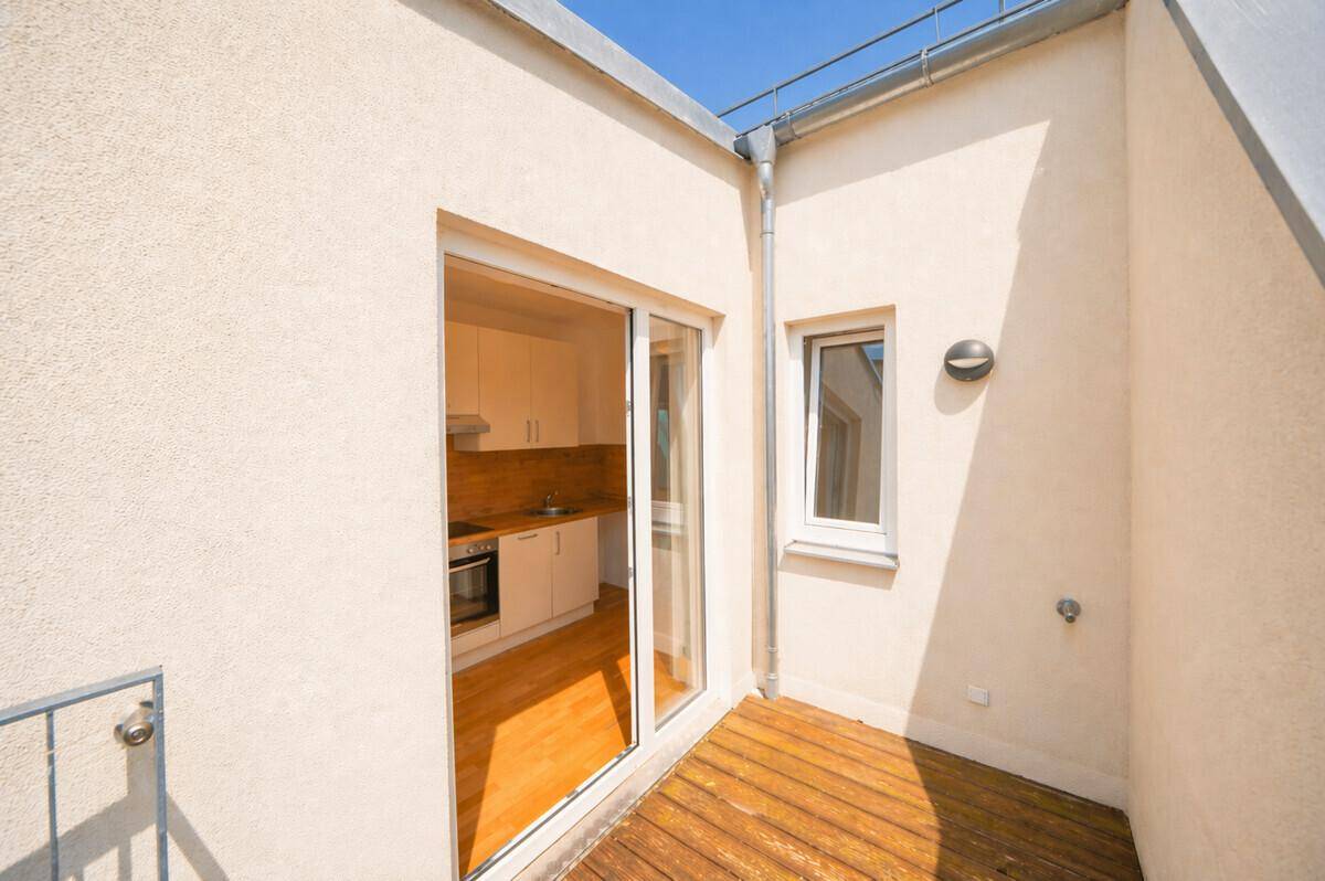 Kleiner Balkon mit Holzbelag und Zugang zur Küche, ideal für eine gemütliche Pause.
