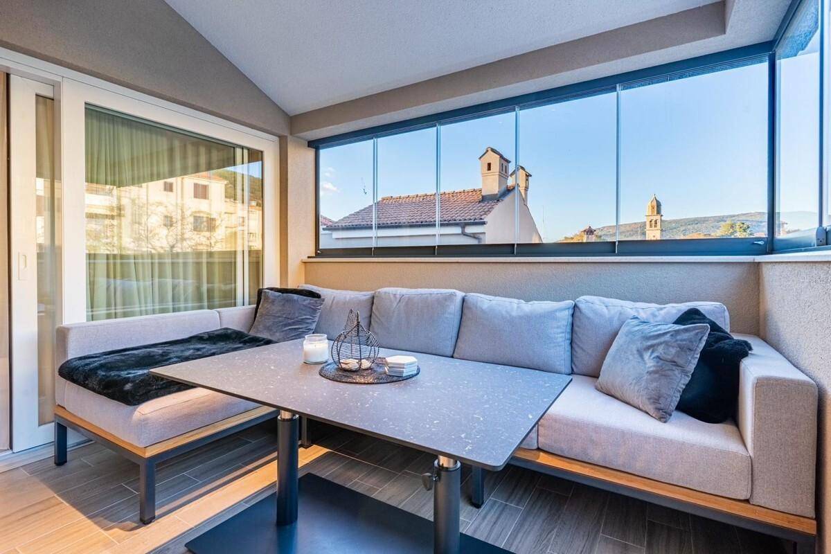 Gemütliche verglaste Loggia mit Sitzecke und Blick auf die umliegenden Gebäude.