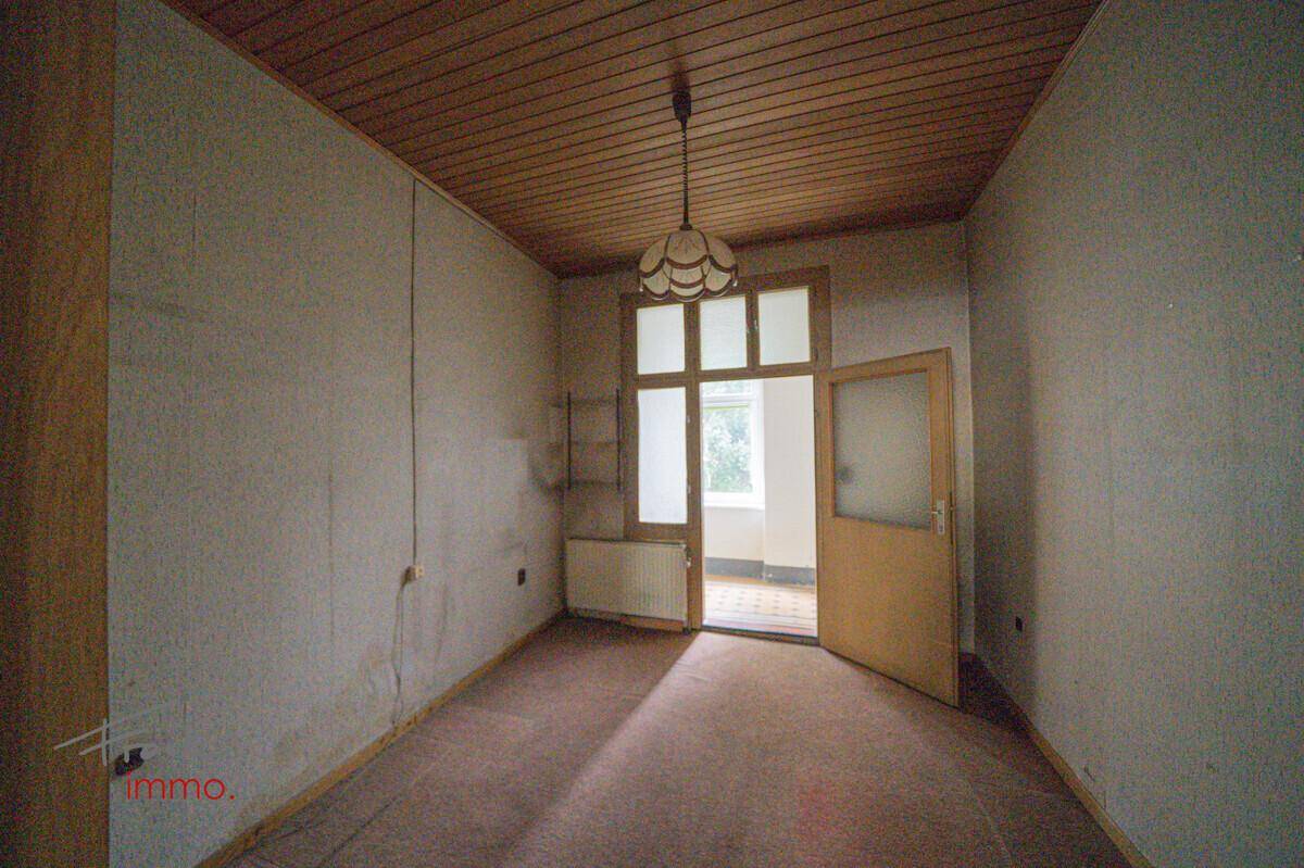 Raum mit Teppichboden, Holzpaneeldecke und einem Fenster, das Licht hereinlässt.