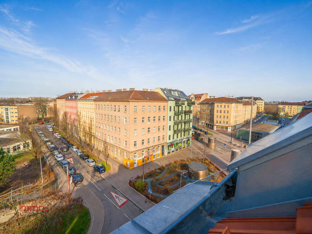 Panoramablick über eine belebte Stadtkreuzung mit historischen Gebäuden und viel Grün.