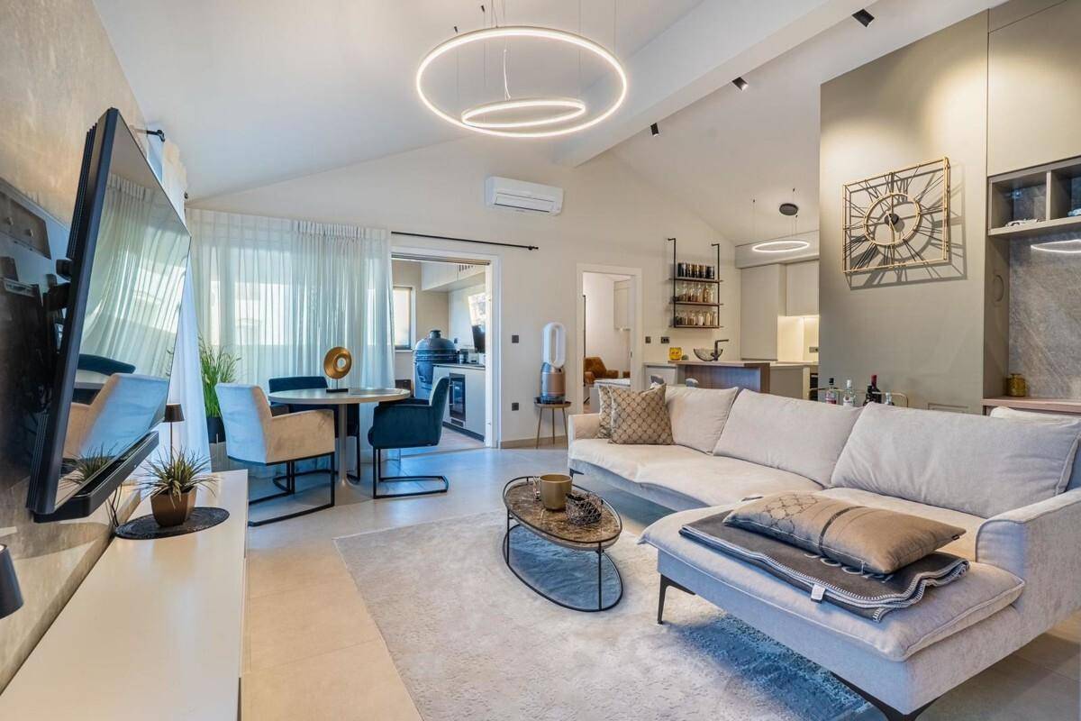 Offener Wohn- und Essbereich mit beigem Sofa, Esstisch und Blick auf die moderne Küche.