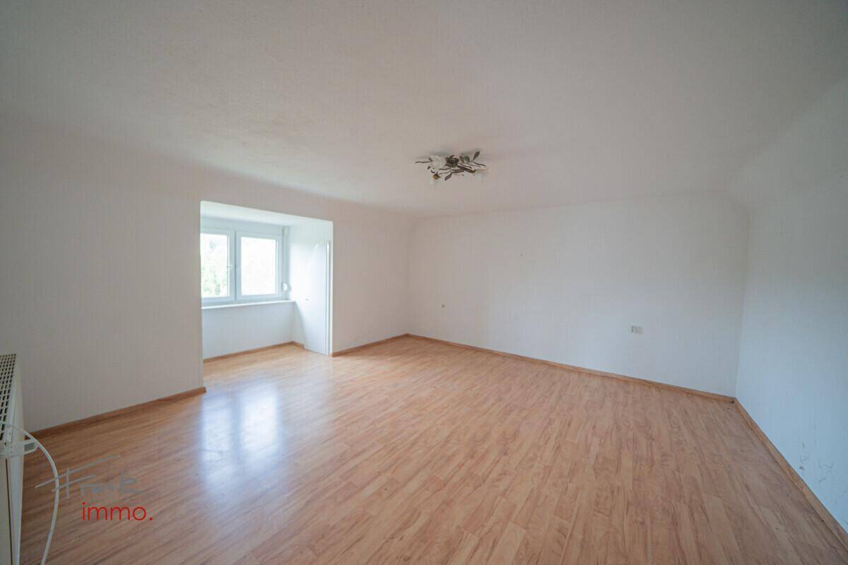 Geräumiges Wohnzimmer mit Laminatboden und einer hellen Fensternische.