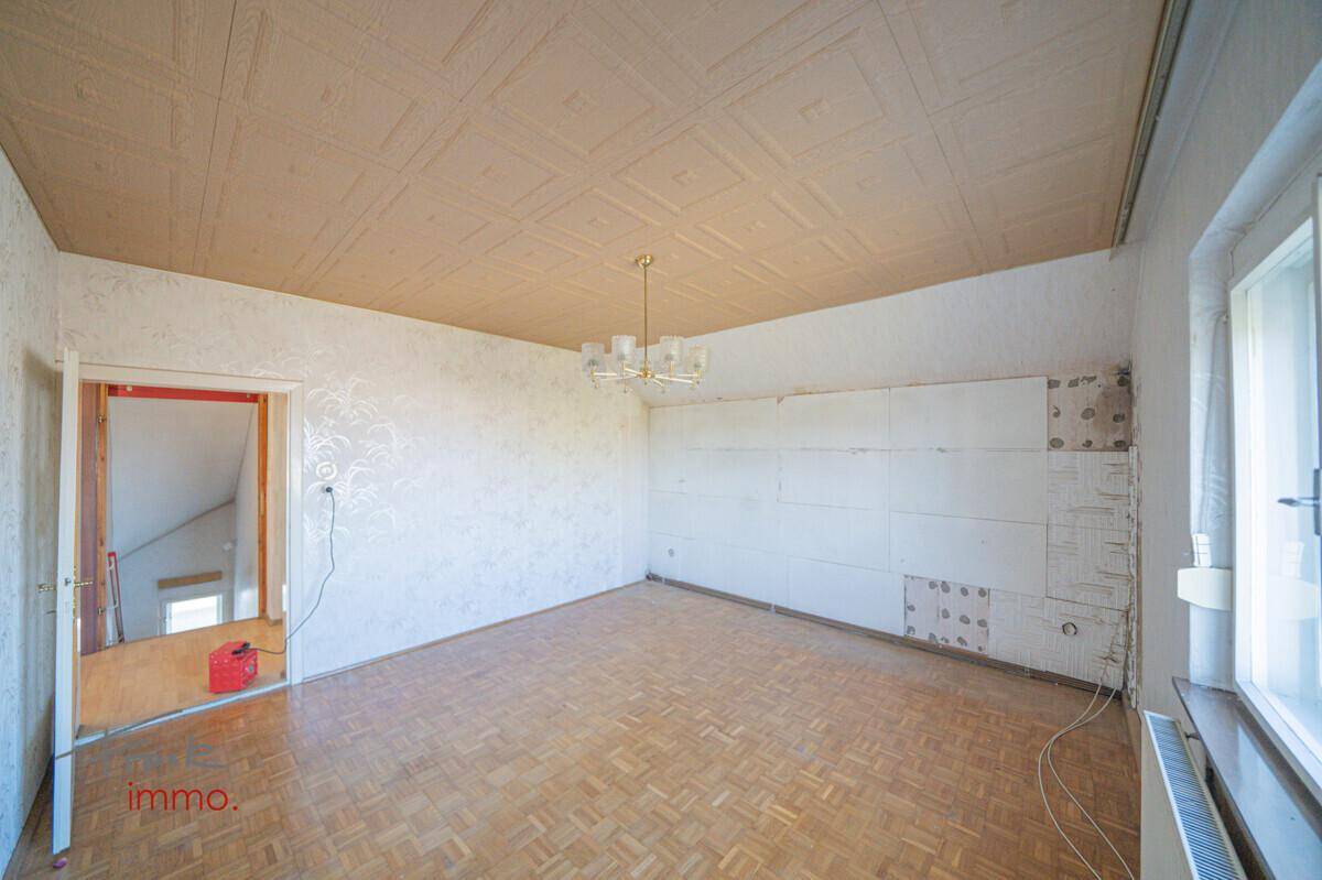Geräumiges Zimmer mit Parkettboden und dekorativer Decke, bereit für eine umfassende Renovierung.
