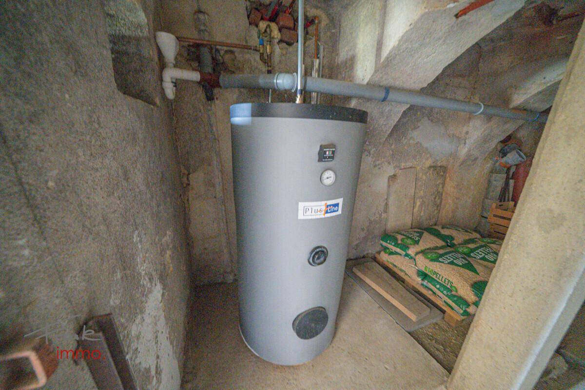 Warmwasserspeicher im Keller mit Rohren und einfacher Ausstattung, für die Warmwasserversorgung.