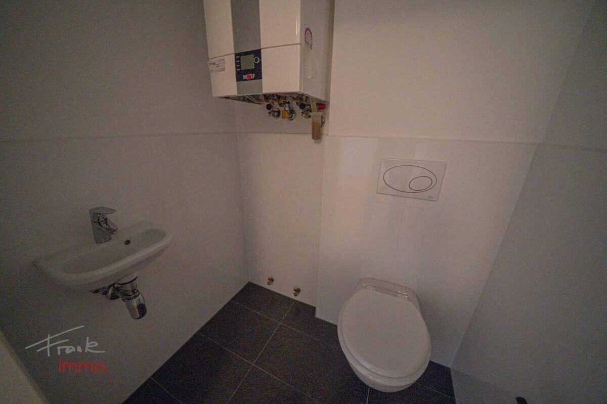 Kleines Gäste-WC mit Toilette, Waschbecken und Warmwasserboiler, funktional und sauber.