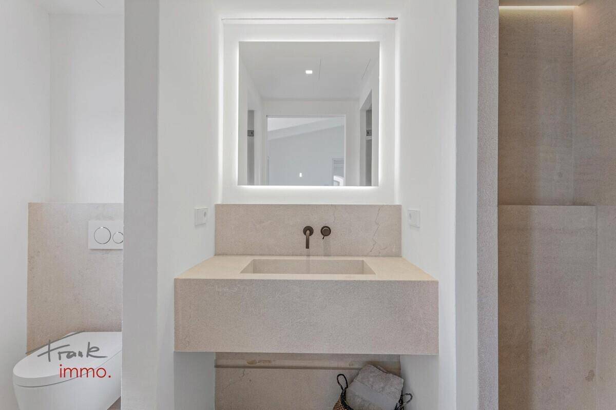 Modernes Badezimmer mit schwebendem Waschtisch, beleuchtetem Spiegel und Wand-WC.