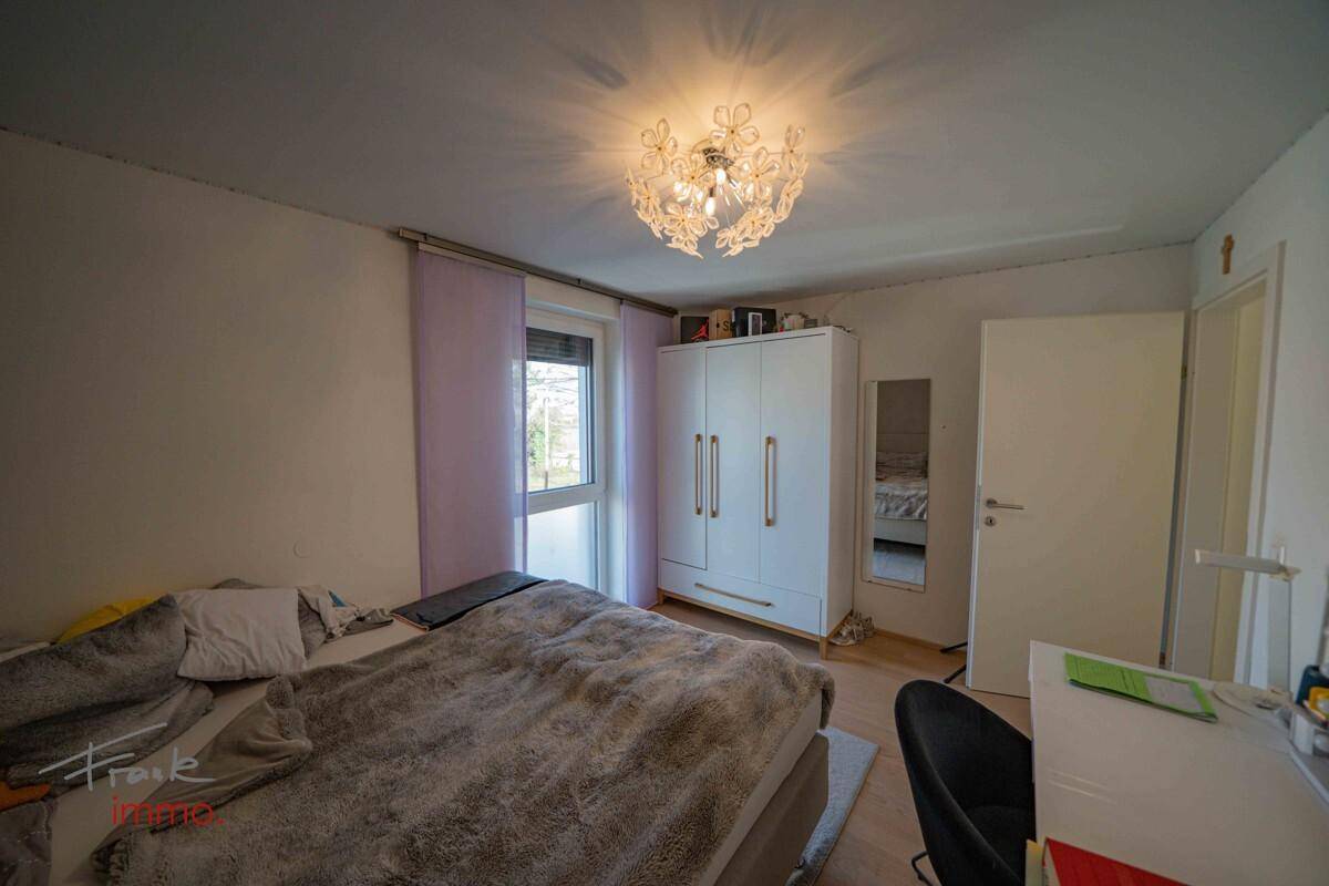 Gemütliches Schlafzimmer mit Doppelbett, Kleiderschrank und Fenster.