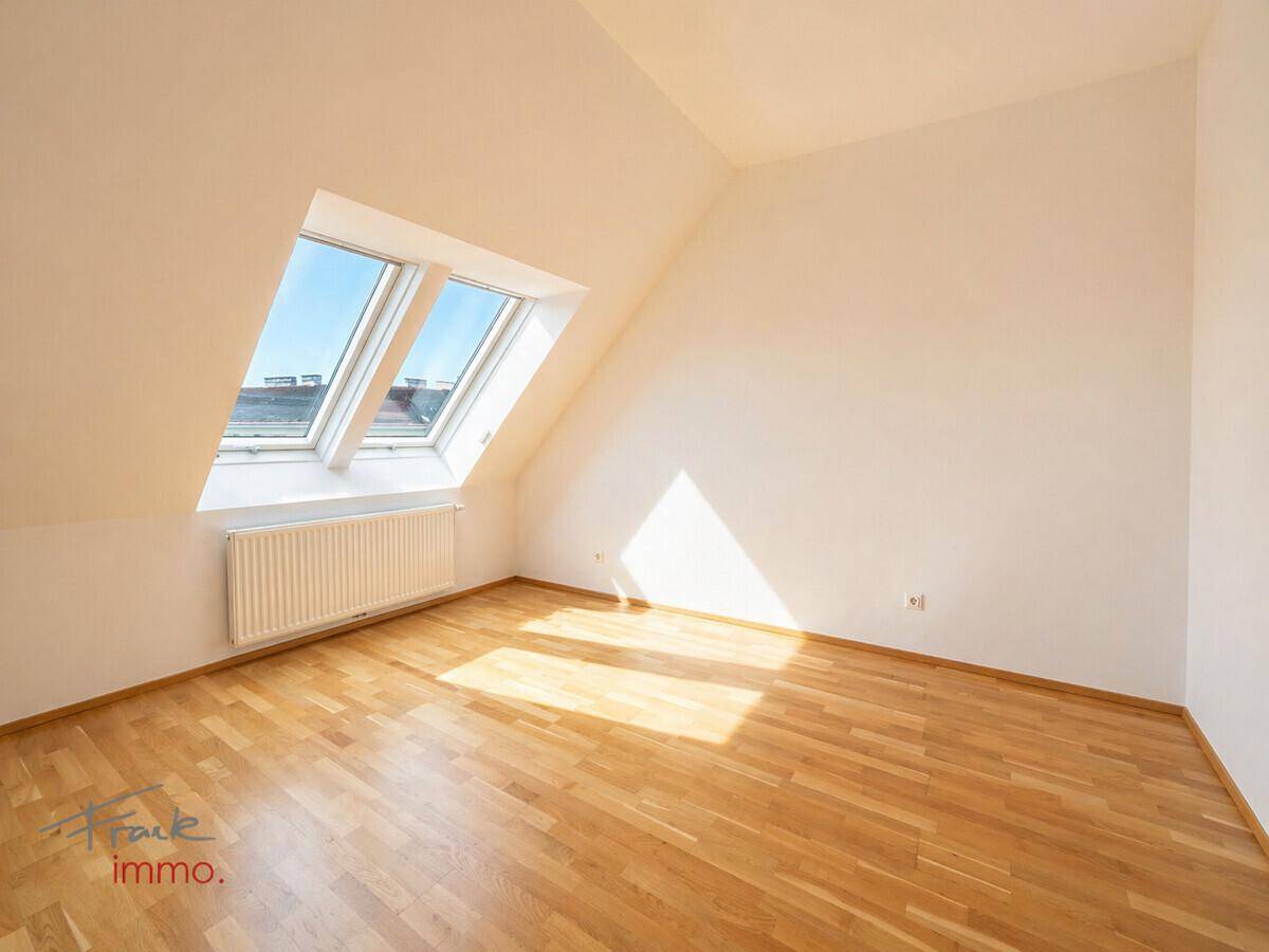Lichtdurchflutetes Dachgeschosszimmer mit Holzboden und zwei Dachfenstern, sehr hell.