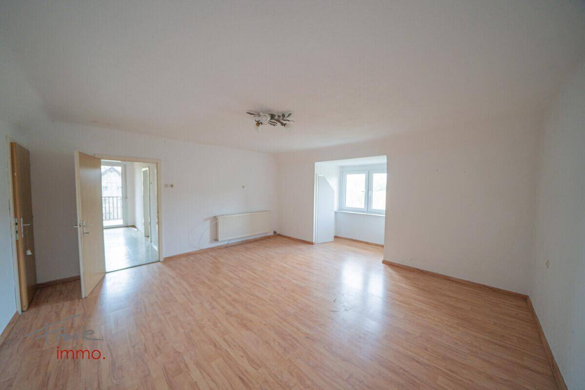 Helles Wohnzimmer mit Laminatboden und Zugang zu einem Außenbereich.