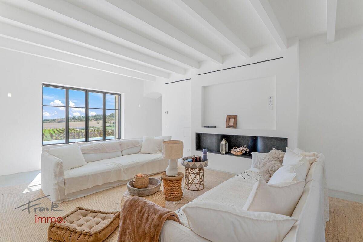 Helles Wohnzimmer mit bequemen weißen Sofas, sichtbaren Deckenbalken und weitem Ausblick.