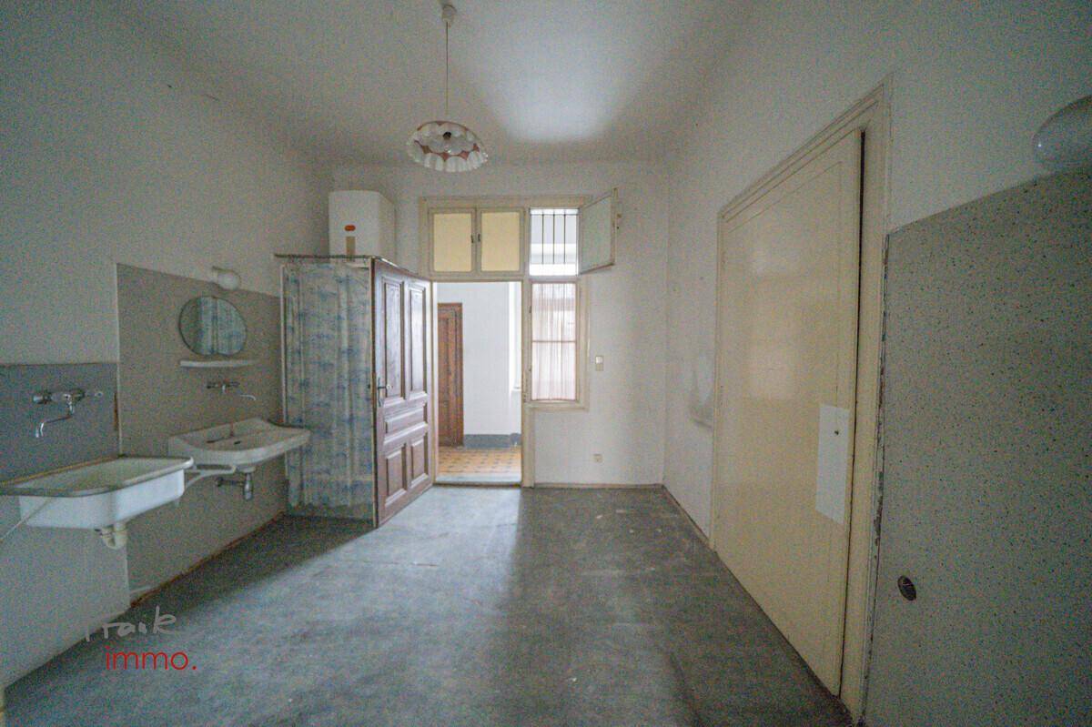 Badezimmer mit zwei Waschbecken, Duschvorhang und Fenster, in renovierungsbedürftigem Zustand.
