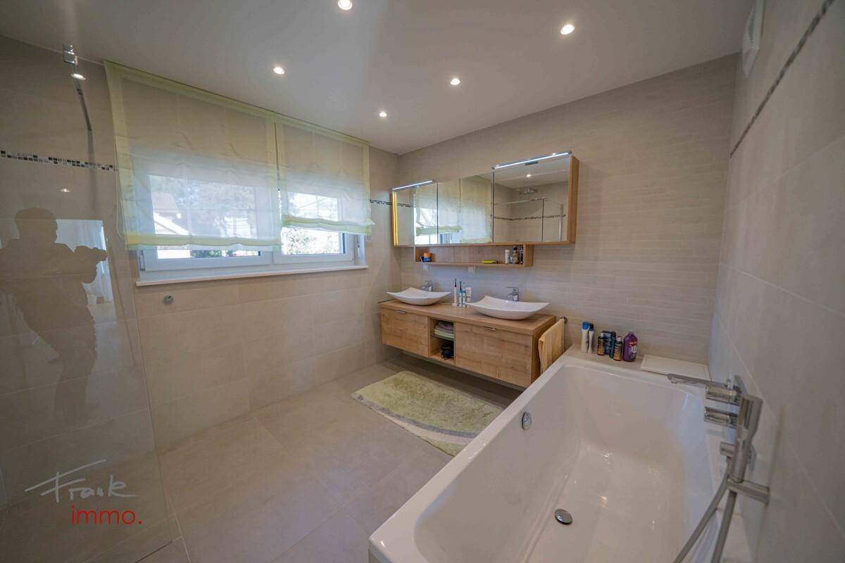Modernes Badezimmer mit Doppelwaschbecken, Badewanne und Fenster.