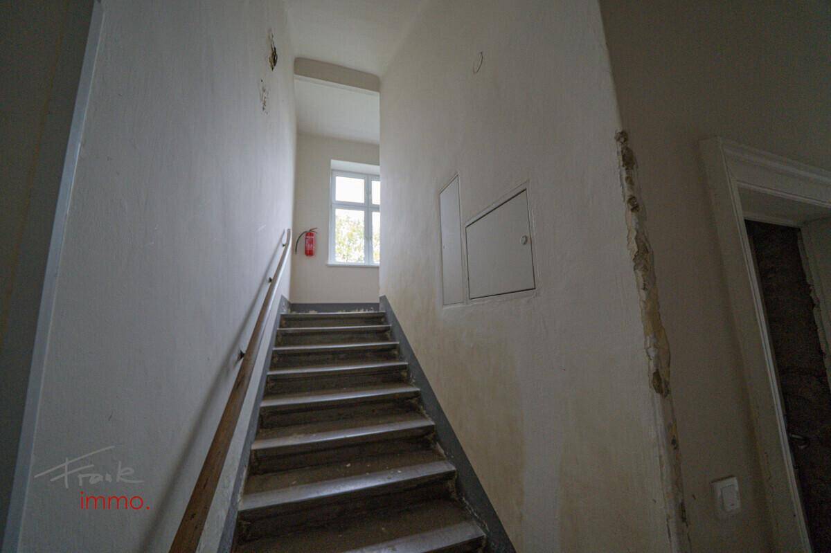 Treppenhaus mit Holzgeländer und Fenster, das natürliches Licht in den Bereich bringt.