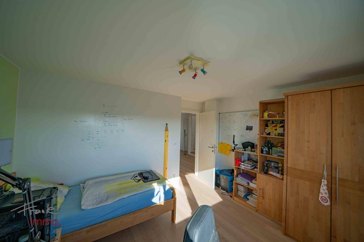 Kinderzimmer mit Holzboden, Schreibtisch und Stauraum.