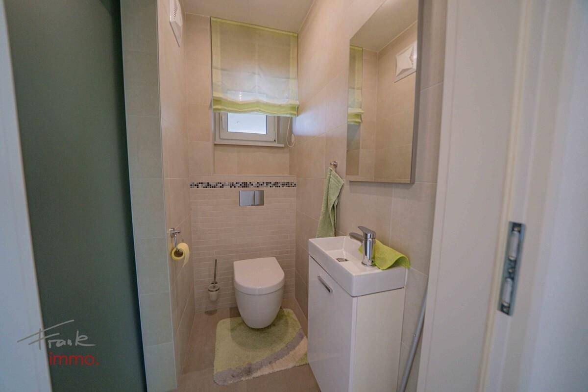 Helles Gäste-WC mit modernen Fliesen, wandhängendem WC und Fenster.